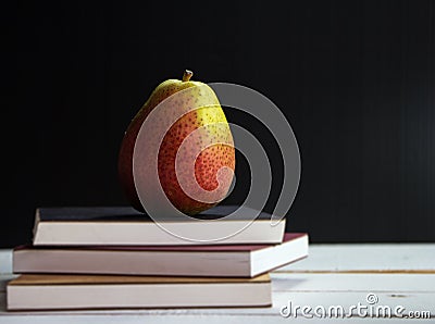 Closeup Pear put on three books stacked on wooden timber board,vintage warm light tone Stock Photo