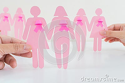 Closeup of people holding pink female figures with ribbons - concept of breast cancer awareness Stock Photo