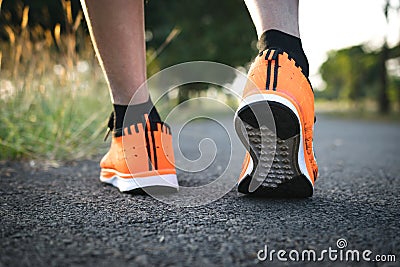 Closeup people walking with orange shoes on road in park for health concept. Stock Photo