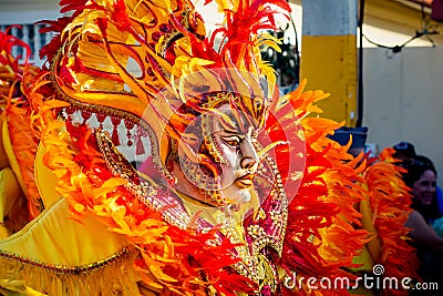 Closeup person in flamboyant costume walks by city street at dominican carnival Editorial Stock Photo