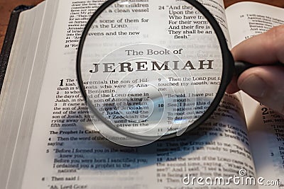 Closeup of a person holding a magnifier and reading the book of Jeremiah from the New Testament Stock Photo