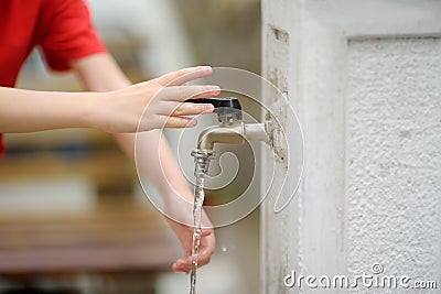 Closeup photo of child washing hands in a city fountain. Little boy drinking clean water from a street pump Stock Photo
