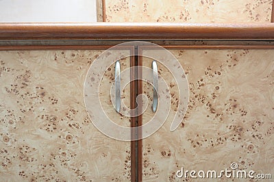 A closeup photo of the doors of a flushed wall wooden wardrobe cardboard cabinets Stock Photo