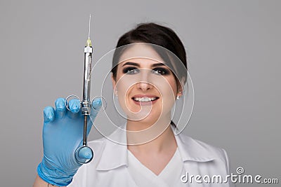 Closeup photo of female dentist holding oral syringe isolated over the grey backgrownd. Stock Photo