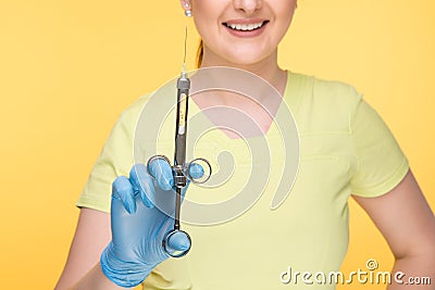 Closeup photo of female dentist holding oral syringe isolated over the yellow backgrownd. Stock Photo