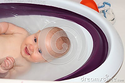 A closeup photo of happy baby enjoying bath time in her baby bath tub Stock Photo