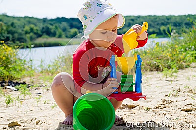 Closeup photo of a little girl. A child plays with the sand on the beach. Stock Photo
