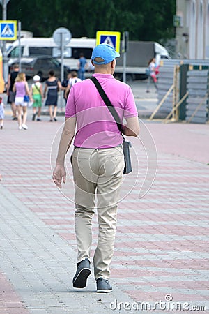 Closeup photo of man in beige tshirt standing isolated on pink background looking attentively at screen of cellphone, browsing web Editorial Stock Photo