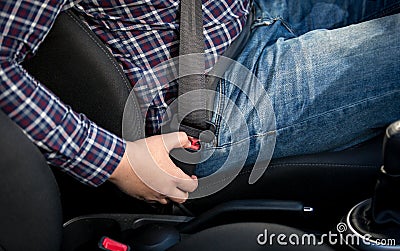 Closeup photo of man seating on drivers seat and fastening belt Stock Photo