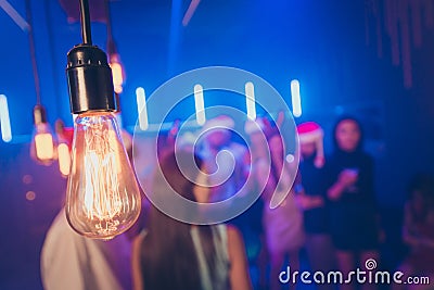 Closeup photo of old-fashioned light bulb making miracle atmosphere party crowd best friends on dance floor blurry focus Stock Photo
