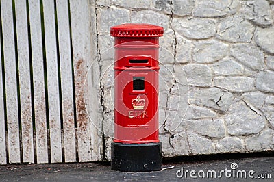 Closeup photo of tiny model British postbox against a stone wall Editorial Stock Photo