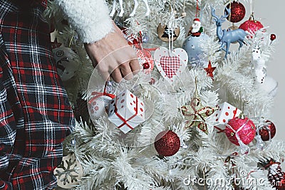 Closeup photo of young woman decorating white Christmas Tree at Stock Photo