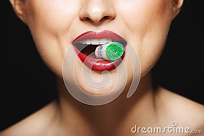 Closeup picture of cheerful girl`s lips holding sweeties with teeth. Stock Photo