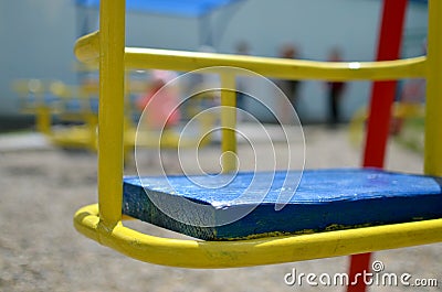 Closeup picture of an iron empty swing in the playground with silhouettes of children Stock Photo