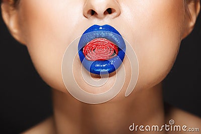 Closeup picture of woman`s colorful lips holding sweeties. Stock Photo