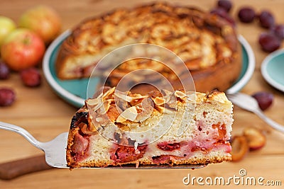 Closeup piece of homemade pie with apples and plums with almond petals. Stock Photo