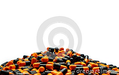 Closeup pile of orange-black capsule pills on white background. Vitamins and supplements. Pharmaceutical industry. Global Stock Photo