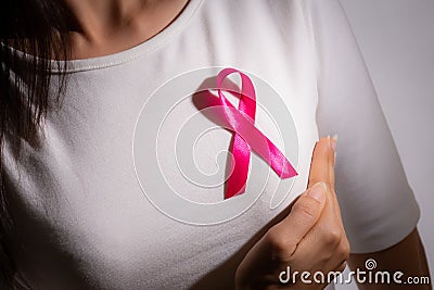 Closeup of pink badge ribbon on woman chest to support breast cancer cause. Healthcare, medicine and breast cancer awareness Stock Photo