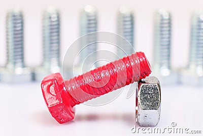 Closeup of pink bolt and nut n a group of galvanized metallic screws. Leadership, dominance, dissimilarity concept Stock Photo