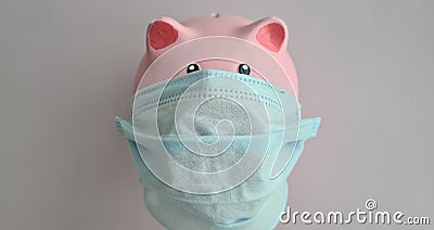 Closeup of pink piggy bank with a medical mask against a pink background Stock Photo