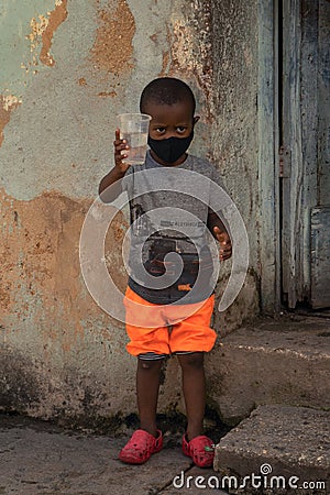 Closeup of a poor Cuban boy toasting a glass of water Editorial Stock Photo