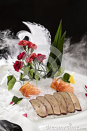 Closeup of pork liver cooked slices on crushed ice and salmon with decorative leaves and flowers Stock Photo
