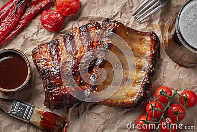 Closeup of pork ribs grilled with BBQ sauce and caramelized in honey on a paper. Tasty snack to beer. Top view. flat lay Stock Photo