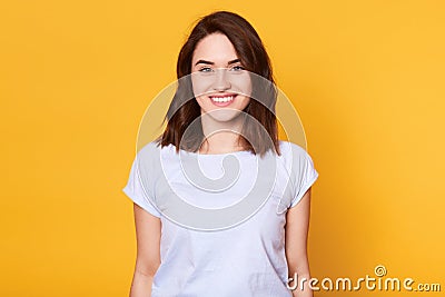 Closeup portrait of attractive woman stands smiling isolater over yellow background and looks directly at camera. Adorable lady Stock Photo