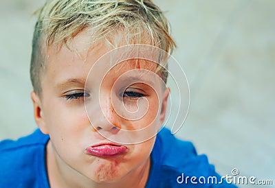 Closeup portrait boy mischievous cute blond close blue eyes, stuck out lip gesture of unwillingness, making freckles Stock Photo