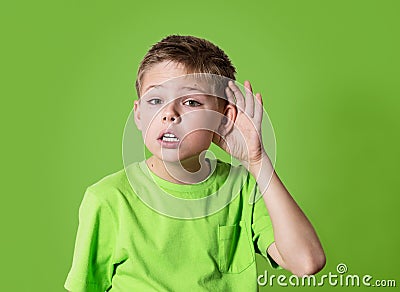 Closeup portrait child hearing something, parents talk, gossips, hand to ear gesture isolated on green background. Stock Photo