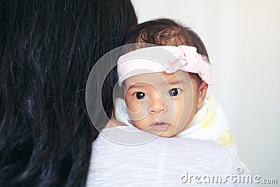 Closeup portrait of cute adorable awake Asian Chinese mixed race newborn baby girl with open eyes lying on parent shoulder Stock Photo