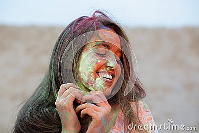 Closeup portrait of emotional brunette woman celebrating Holi colors festival at the desert Stock Photo