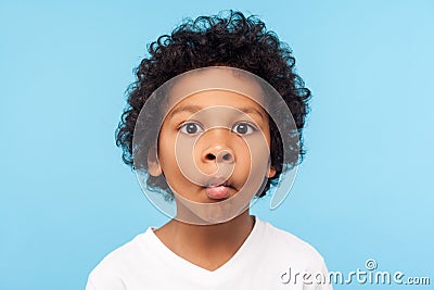 Closeup portrait of funny goofy little boy with curly hair making fish face with pout lips and big eyes Stock Photo