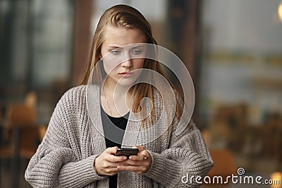 Closeup portrait funny sad young girl looking up thinking seeing bad news sms comment trolling message photos phone in Stock Photo