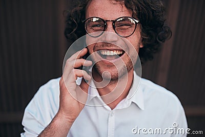 Closeup portrait of happy handsome young businessman making a phone call while walking outdoors wearing white shirt and spectacles Stock Photo