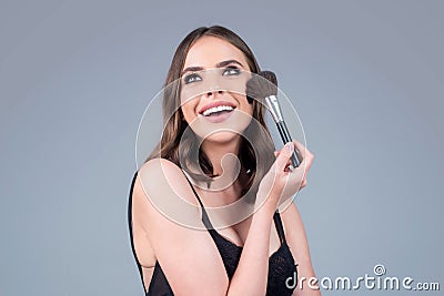 Closeup portrait of a happy smilin model with makeup blusher brush and bright makeup on a face. Portrait of a girl with Stock Photo