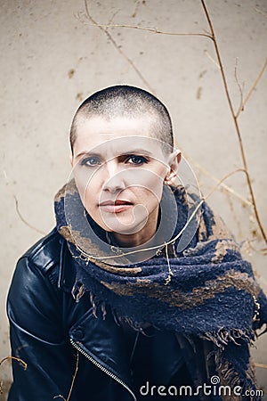 Closeup portrait of sad beautiful Caucasian white young bald girl woman with shaved hair head in leather jacket and scarf Stock Photo