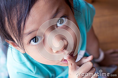 Closeup portrait secretive asian child girl placing finger keep quiet gesture Stock Photo