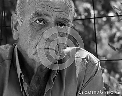 Closeup portrait of a serious old greek retired male who smokes a cigarette with a smile, in black and white Stock Photo