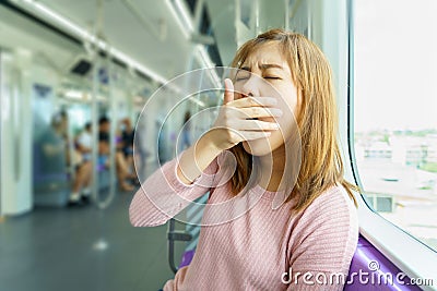 Closeup portrait sleepy, yawn, close eyes young woman in sky train after long hour trip. Stock Photo
