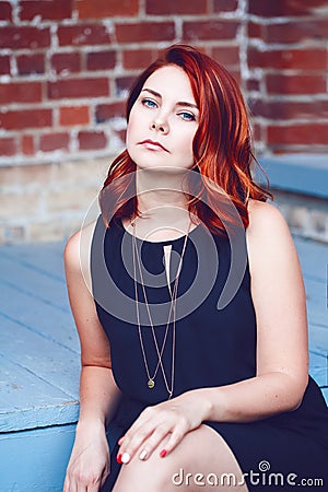 Closeup portrait of smiling middle aged white caucasian woman with waved curly red hair in black dress looking in camera Stock Photo