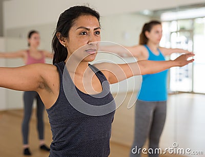 Hispanic woman doing warmup during group workout at gym Stock Photo