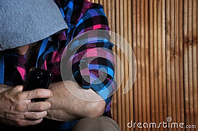 Closeup portrait of strong hand hipster man in the hood holds ph Stock Photo