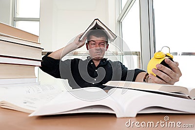 Closeup portrait of white man surrounded by tons of books, alarm clock, stressed from project deadline, study, exams Stock Photo