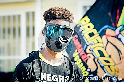 Closeup portrait of young dominican man in black mask against colorful flag Editorial Stock Photo