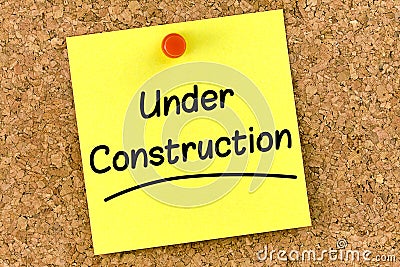 Closeup post it note on corkboard with under construction message on it Stock Photo