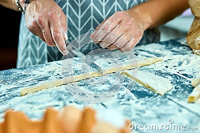Closeup process making homemade pasta. Chef cook cutting with knife fresh dough for italian traditional pasta to thin ribbon. Stock Photo