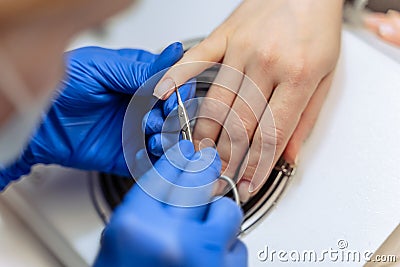 Closeup process of professional Female manicure master at beauty salon removes dry cuticle skin near nails cutting it Stock Photo