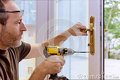 Closeup of a professional locksmith installing or repairing a new deadbolt lock Stock Photo