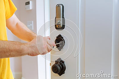 Closeup of a professional locksmith installing or repairing a new deadbolt lock Stock Photo